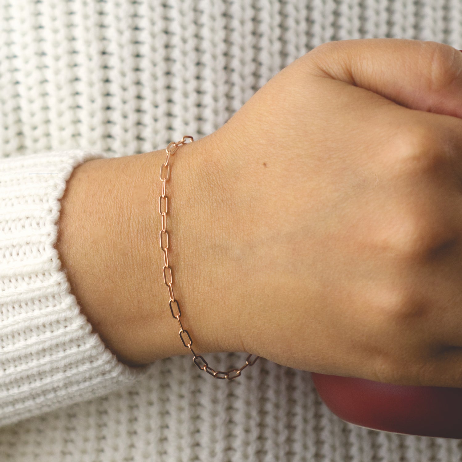 Woman wearing a 14K rose gold fill paperclip chain bracelet with a dainty style (medium) link size