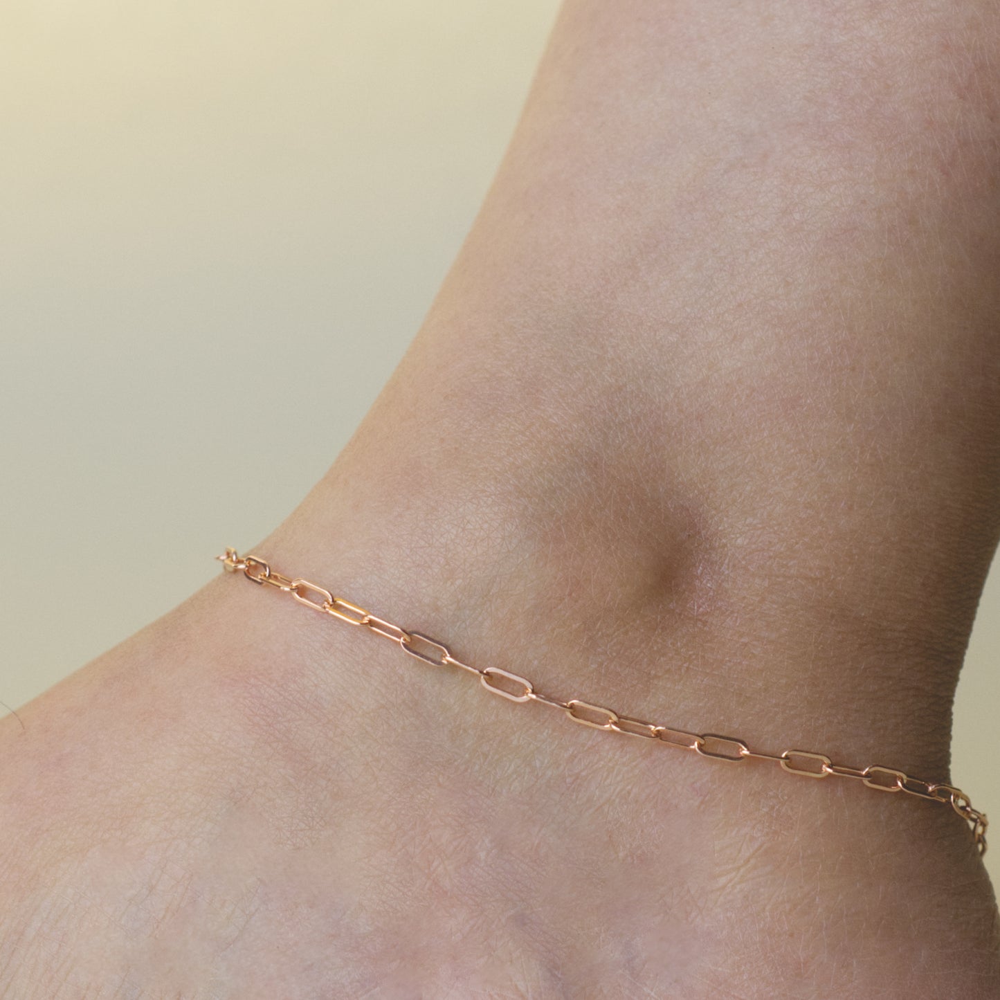 Woman wearing a 14K rose gold fill paperclip chain anklet with a dainty style (medium) link size
