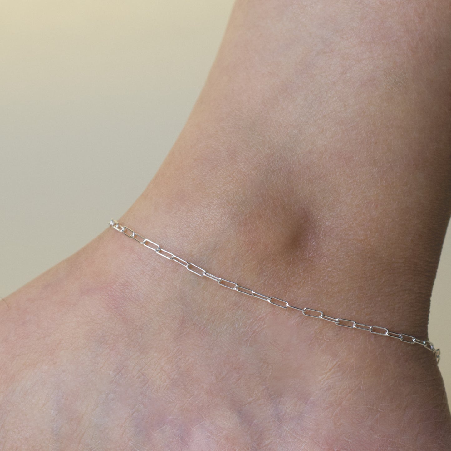 Woman wearing a 925 sterling silver paperclip chain anklet with a minimalist style (small) link size