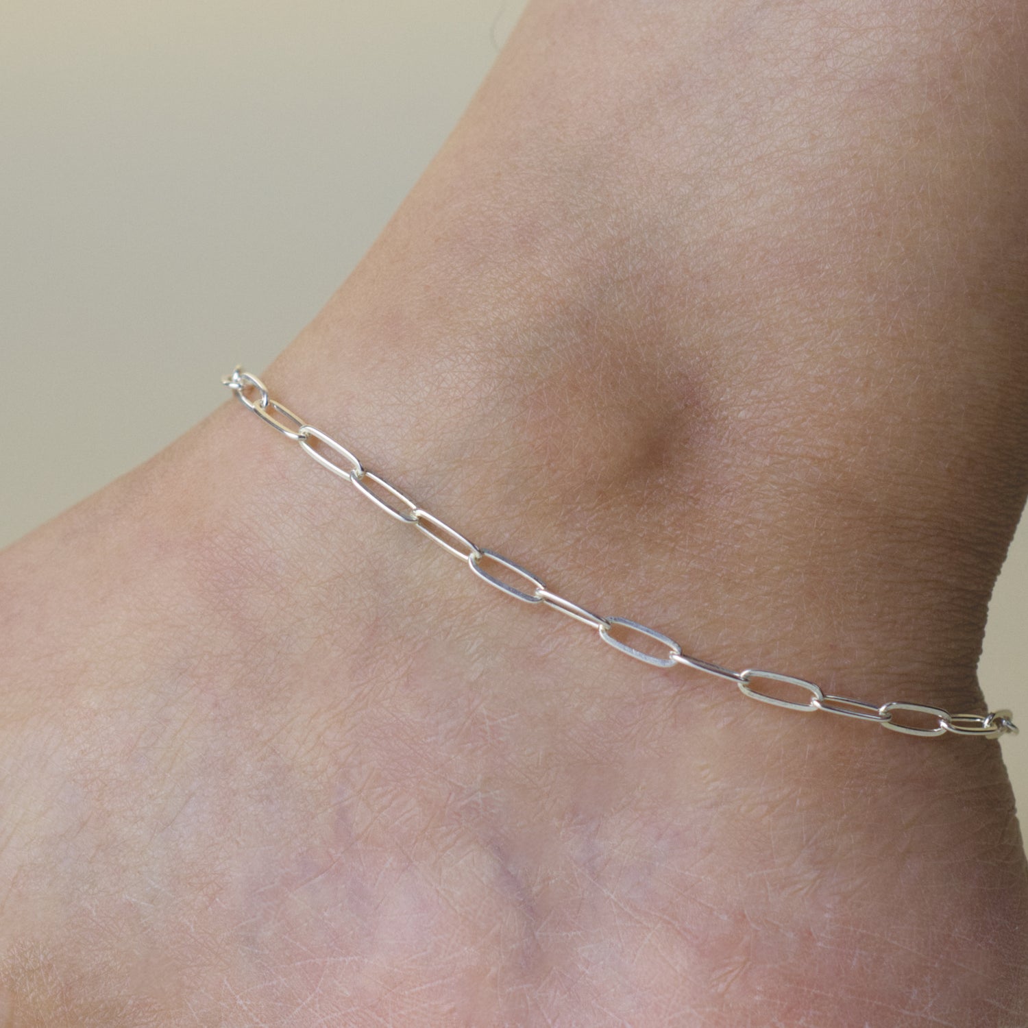 Woman wearing a 925 sterling silver paperclip chain anklet with a classic style (large) link size