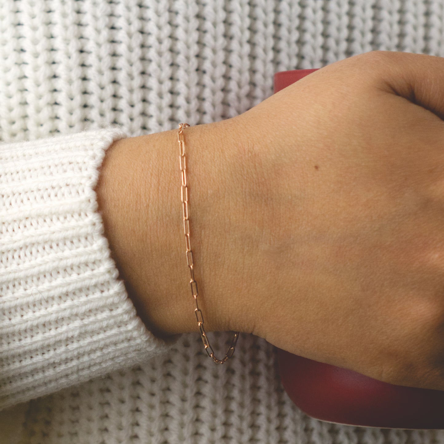 Woman wearing a 14K rose gold fill paperclip chain bracelet with a minimalist style (small) link size