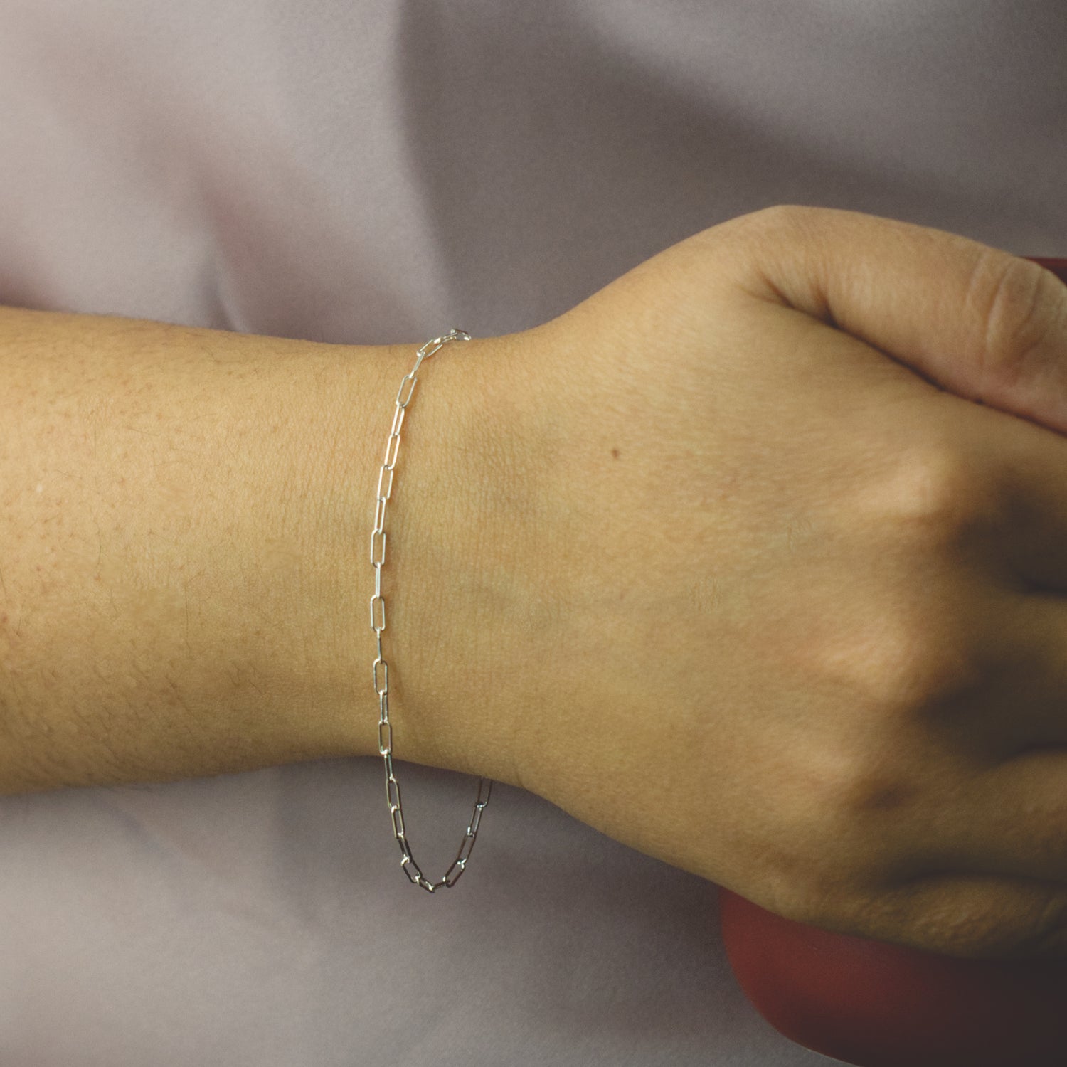 Woman wearing a 925 Sterling Silver paperclip chain bracelet with minimalist style (small) link size