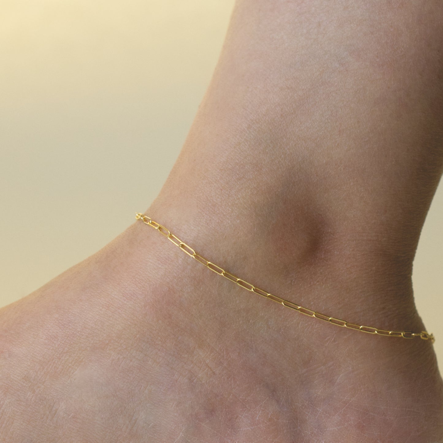 Woman wearing a 14K gold fill paperclip chain anklet with a minimalist style (small) link size