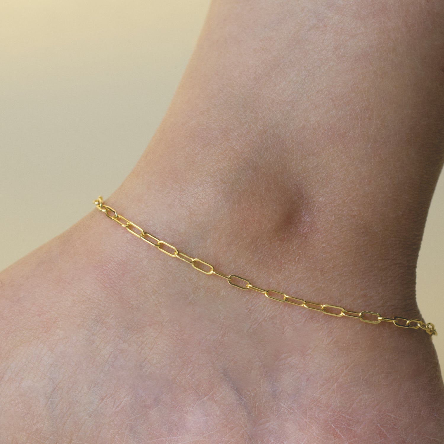 Woman wearing a 14K gold fill paperclip chain anklet with a dainty style (medium) link size