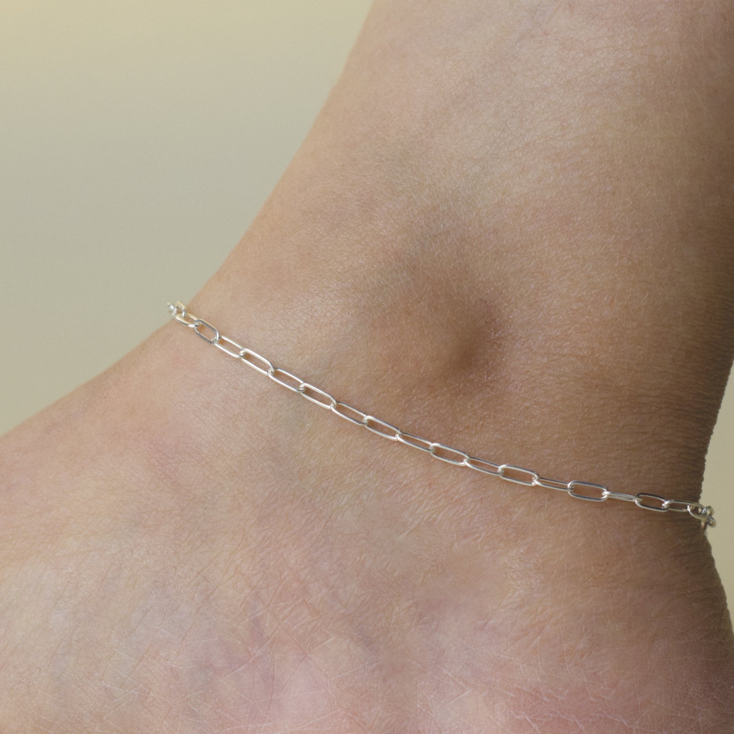 Woman wearing a 925 sterling silver paperclip chain anklet with a dainty style (medium) link size